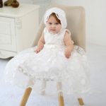 Abito da battesimo online bianco in pizzo con cappellino e cintura con fiocco decorativo collezione 2021