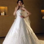 Vestido de novia de corte A clásico  confeccionado en satèn con muchas decoraciones de encaje y pedrería en el corpiño, la falda y la cola