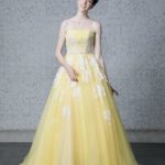 Abito da sposa giallo fatto in tulle il bustino stretto è impreziosito da perline, cristalli e delicati ricami di pizzo bianco