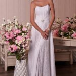 Abito da sposa scivolato realizzato in chiffon e pizzo con corpetto dallo scollo sorriso drappeggiato con fascia in vita decorata con una spilla