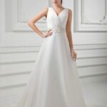 Abito da sposa scollo V realizzato in organza e raso con spalline e bustino drappeggiato, cintura ricamata delicatamente con motivi floreali