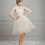 Vestido de novia corto en tul estilo años 50 con falda ancha, el corpiño drapeado presenta un tul semitransparente