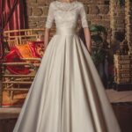 Vestido de novia tradicional color marfil con busto de encaje de pedrería, manga corta, cinturilla entallada