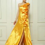 Vestido de fiesta largo de un hombro color amarillo confeccionado en satèn decorado en el hombro con muchos vuelos de tela