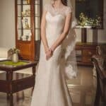 Abito da sposa elegante colore avorio per una donna romantica fatto in pizzo con trasparenze nel decollette e maniche corte