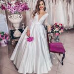 White bespoke wedding dress with long lace sleeves and a sensual deep V-neckline